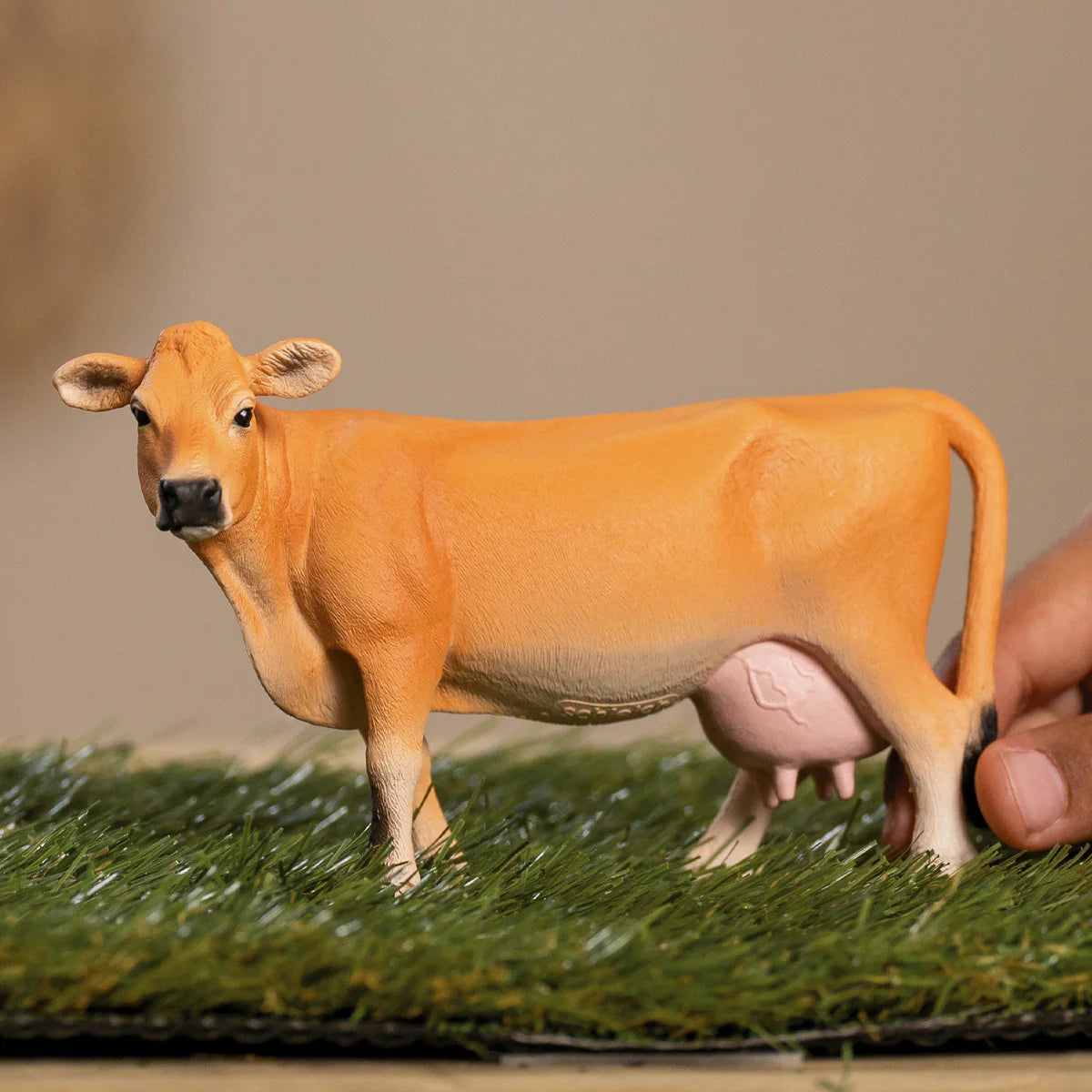 Model cow on a grassy surface with a blurred background