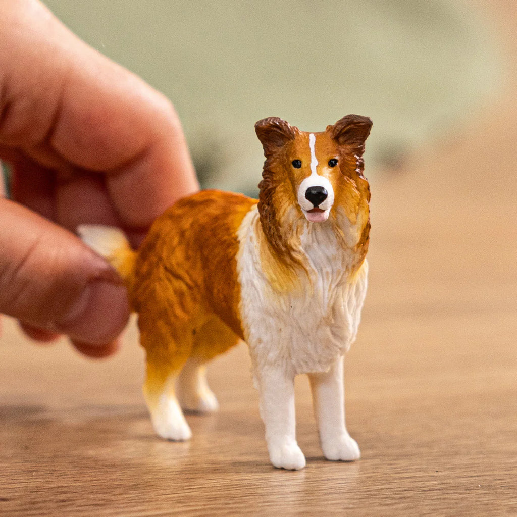 Hand holding a detailed dog figurine on a wooden surface