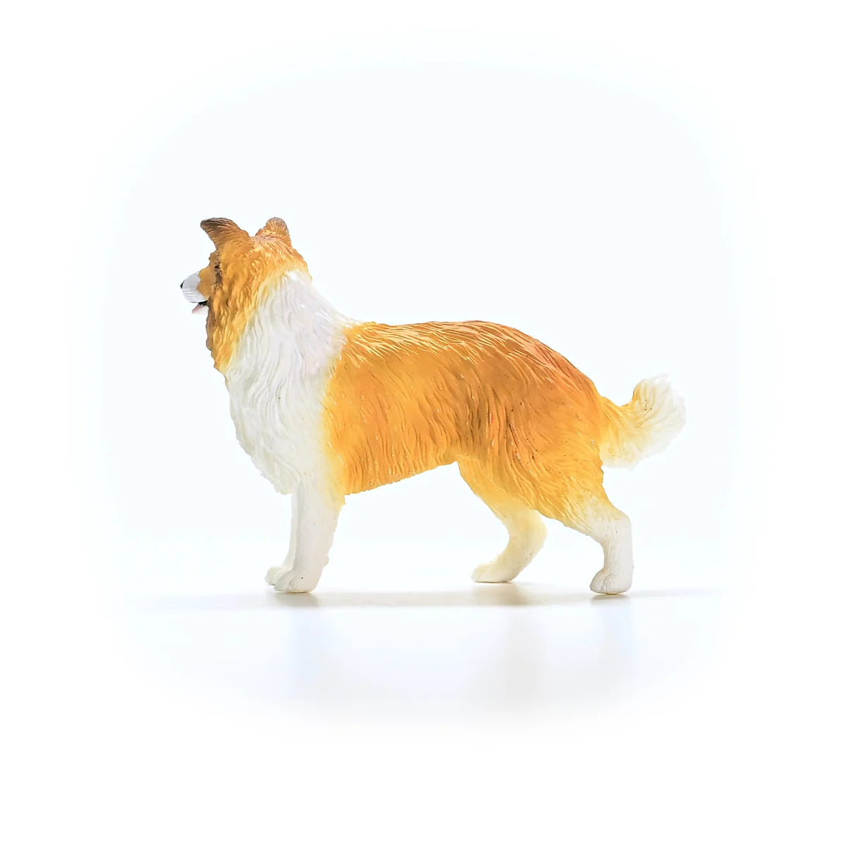 Toy dog figure with a white and brown coat on a white background