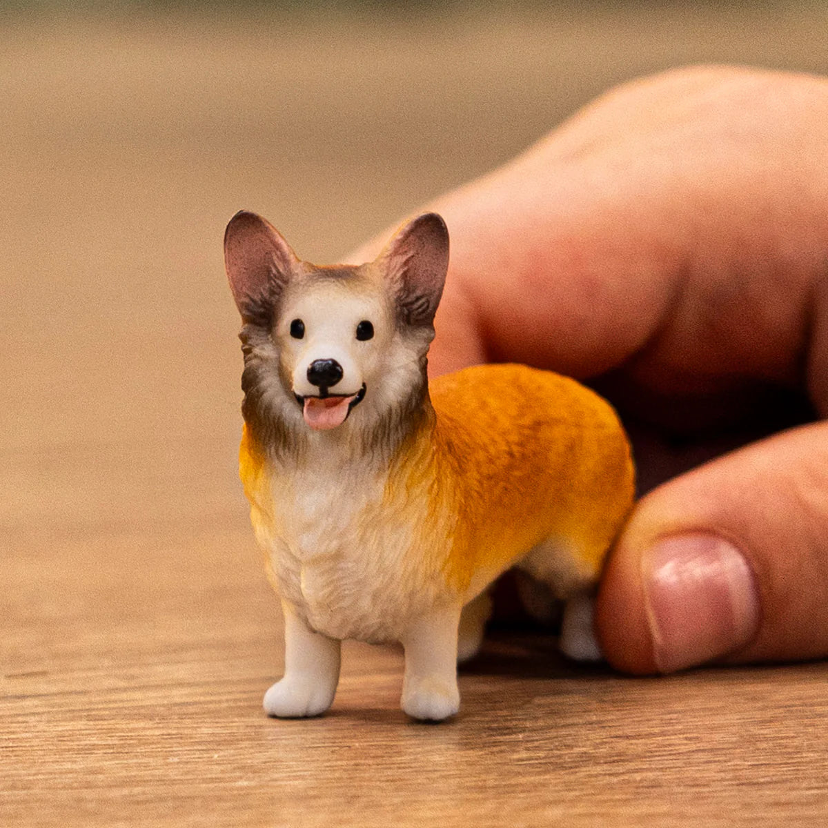 Small dog figurine held between fingers on a wooden surface