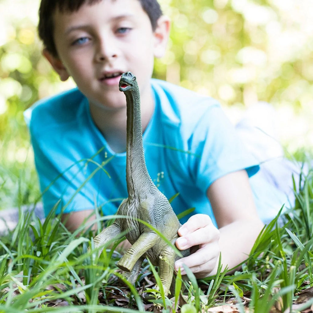 Child playing with a dinosaur toy outdoors