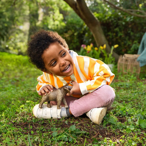 Child playing with a toy elephant in a park