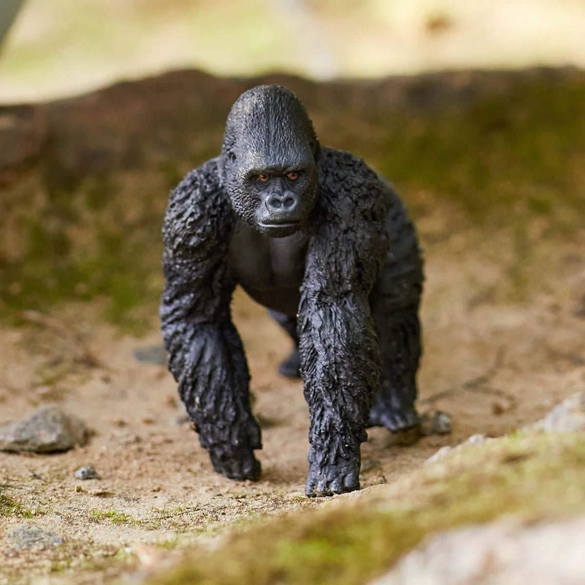 Gorilla figurine standing on a natural ground with blurred background