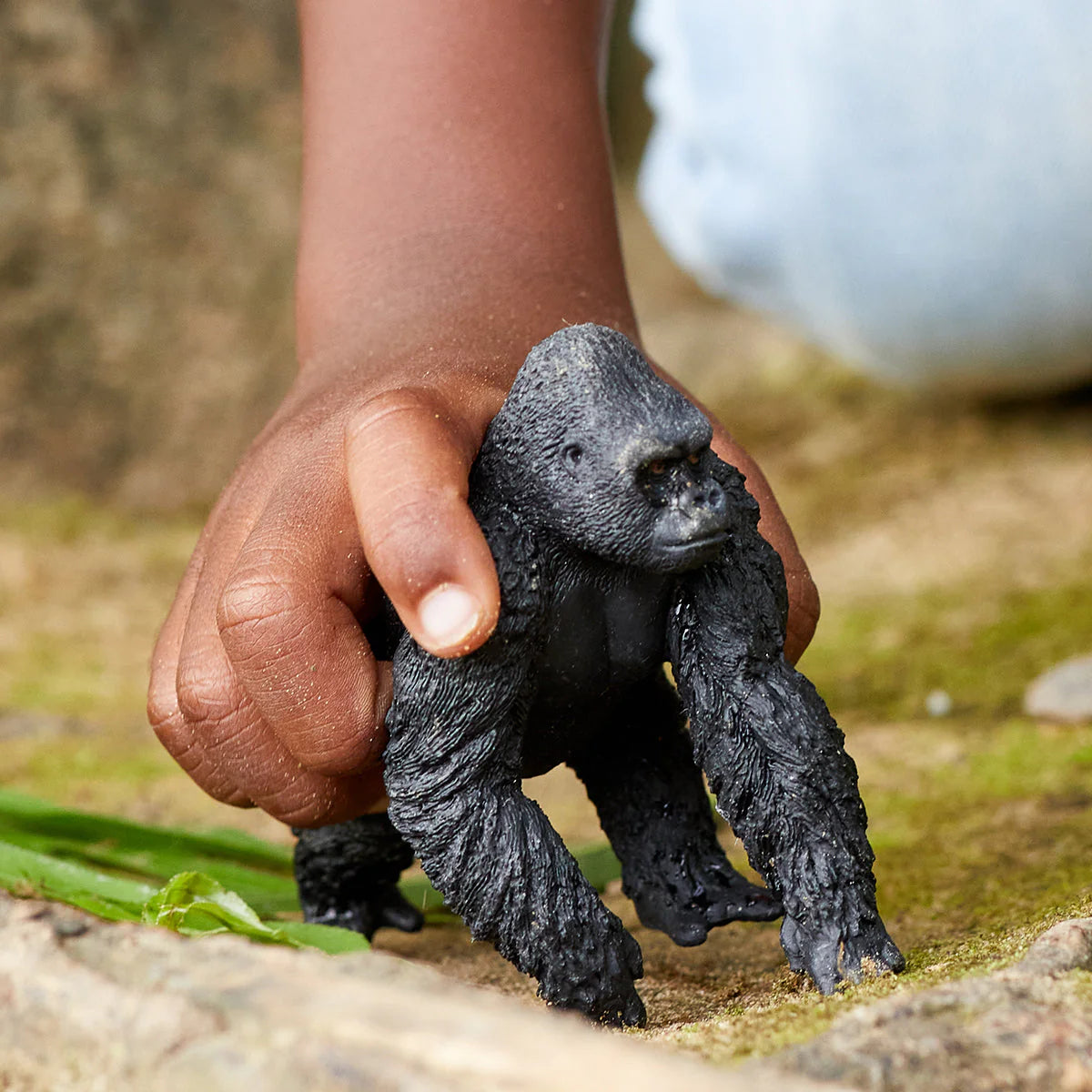Hand holding a toy gorilla figure outdoors