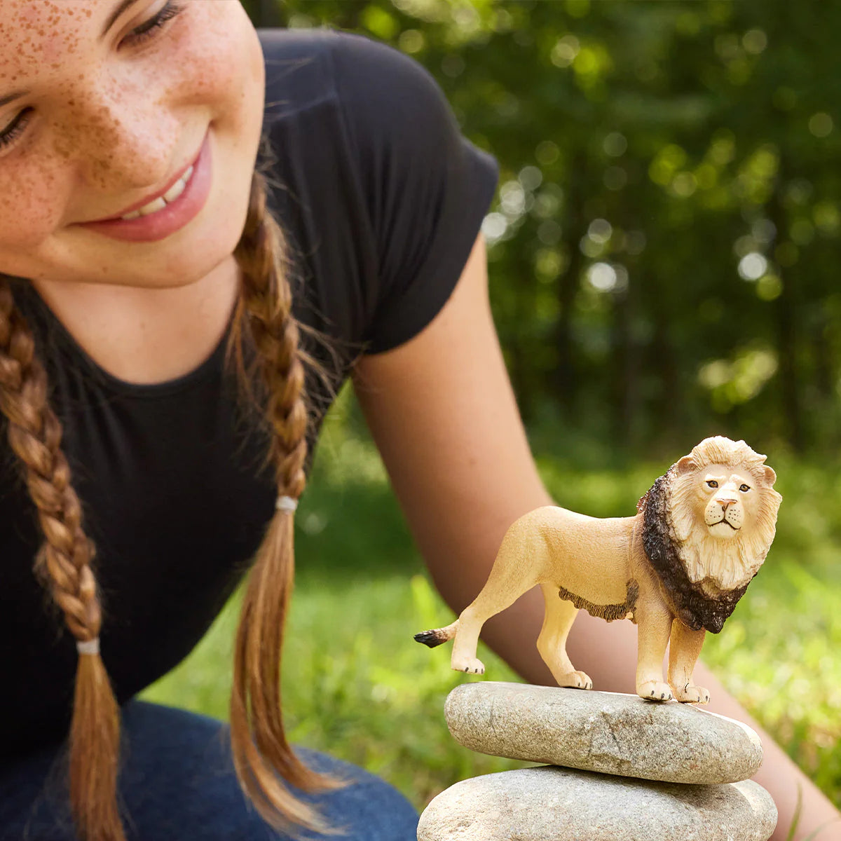 Person with a lion figurine on a rock outdoors