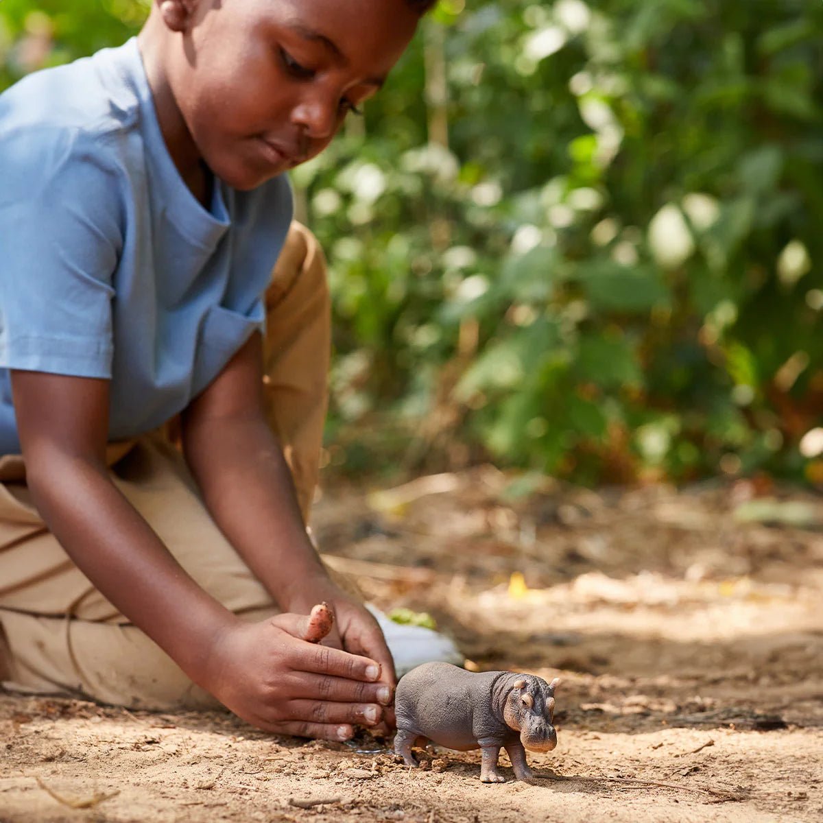 Child interacting with a small animal in a natural setting