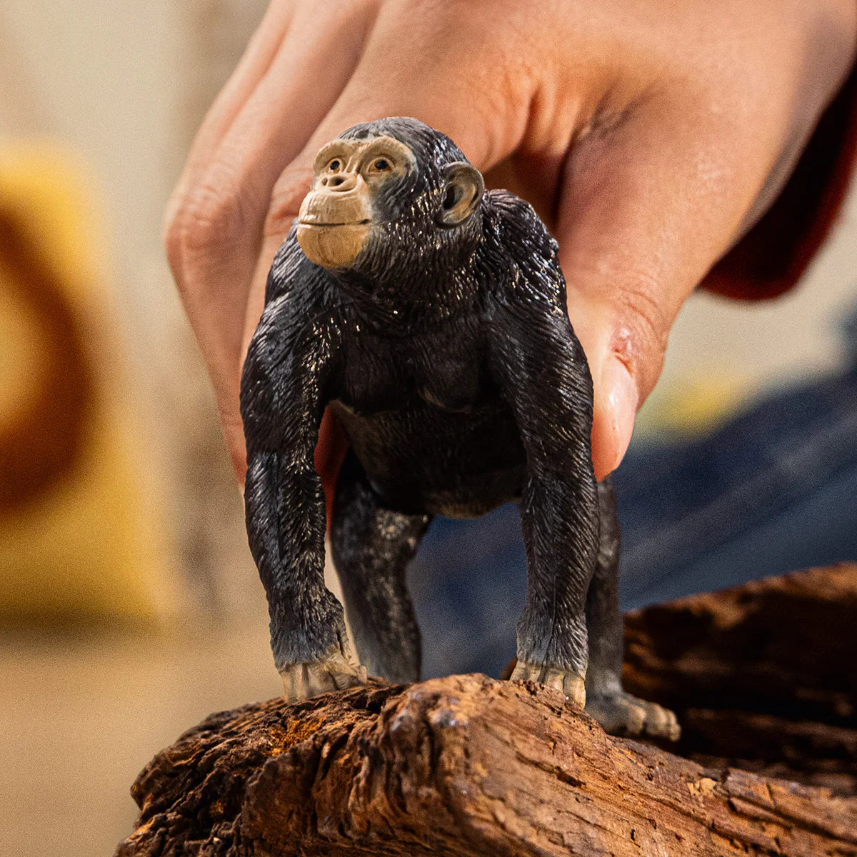 Toy monkey figure on a wooden log with a blurred background