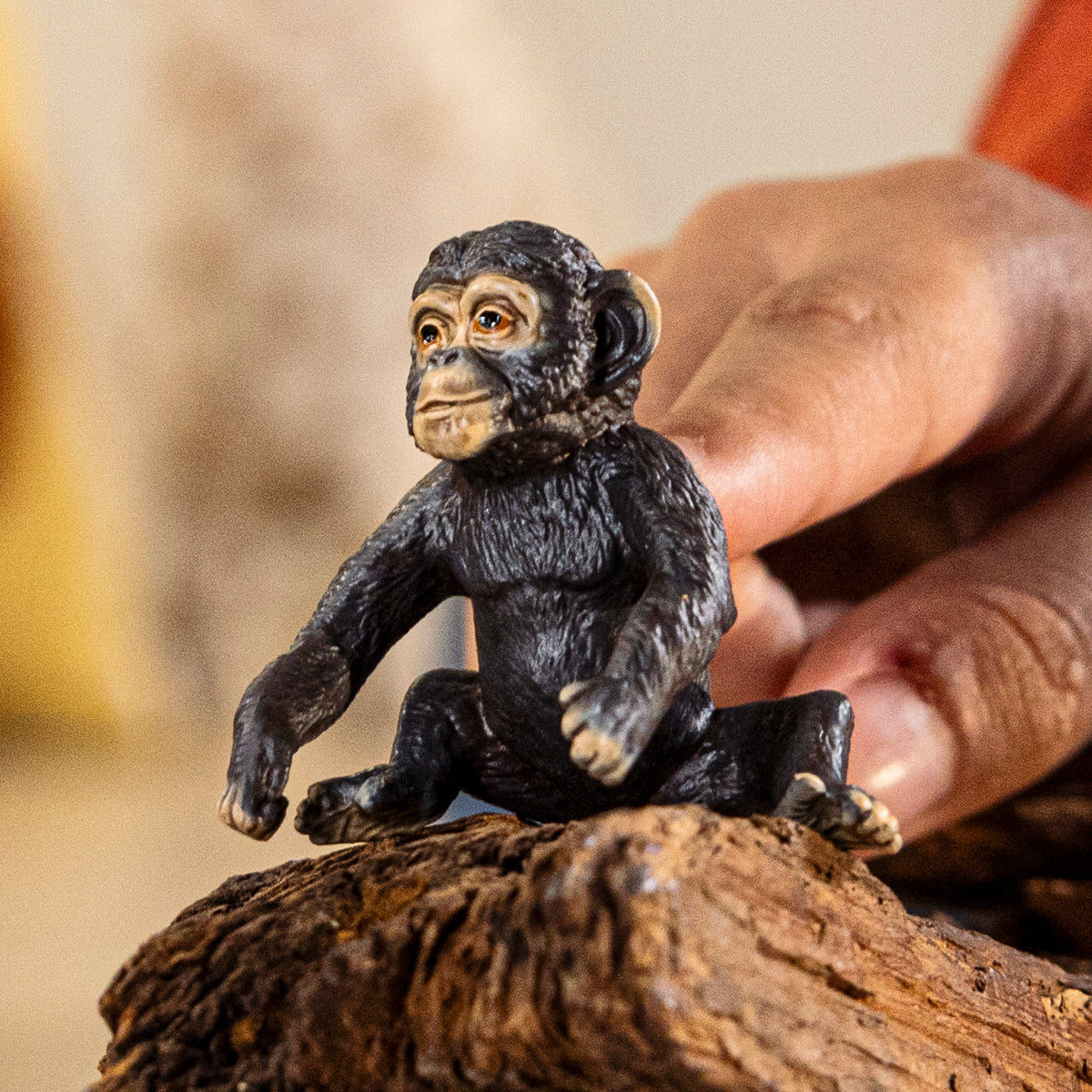 Small monkey figurine held by a hand on a wooden surface