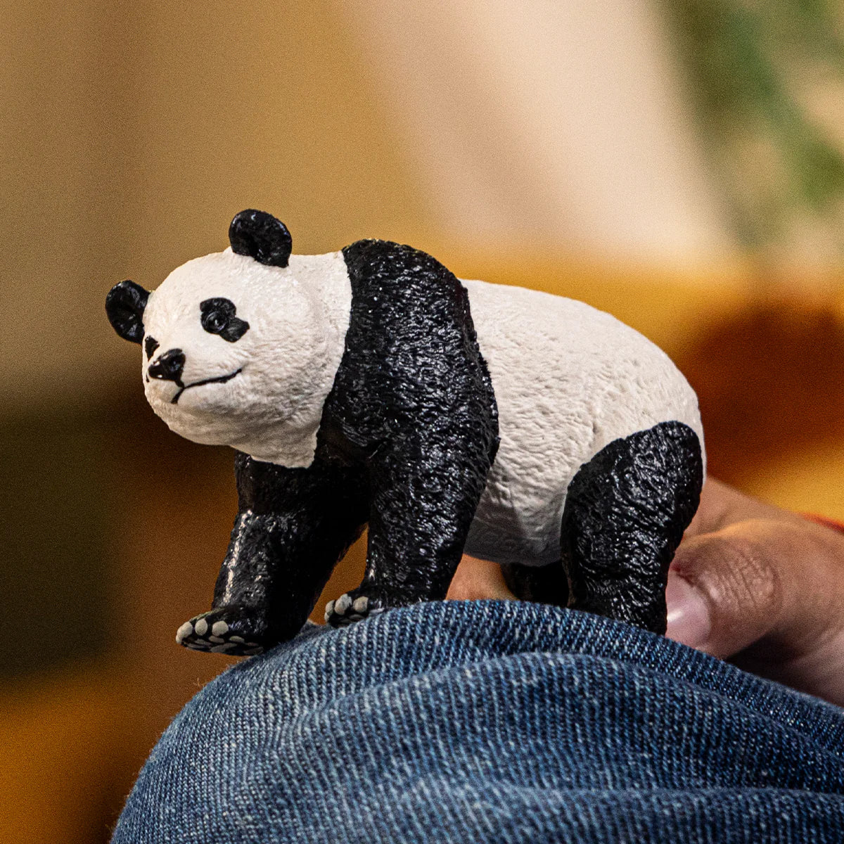 Panda figurine held by a person with a blurred background