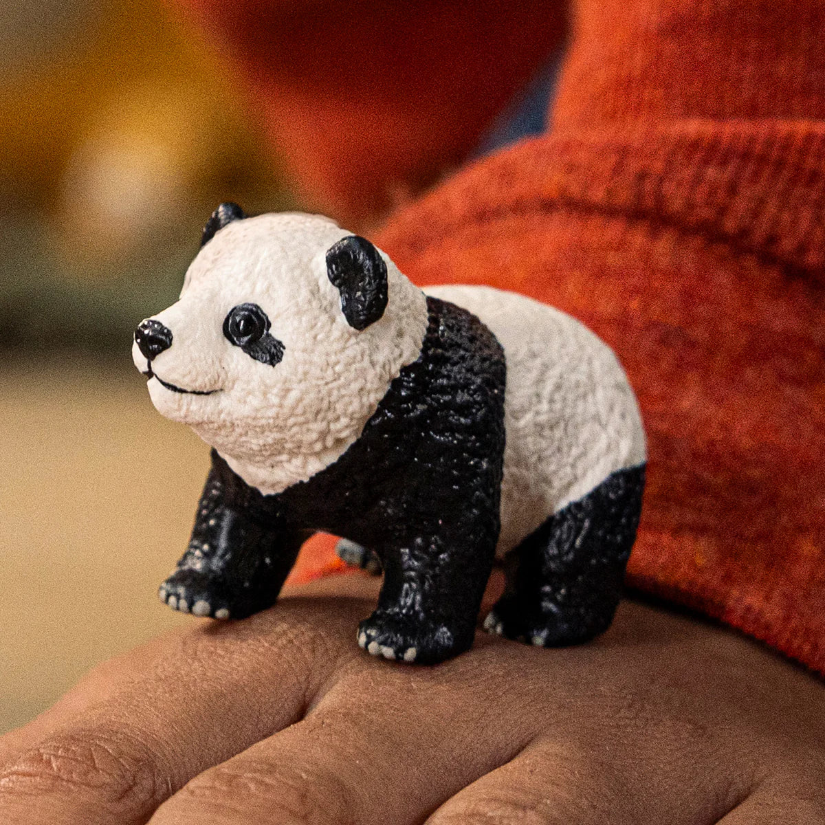 Panda figurine held in a hand with a blurred background