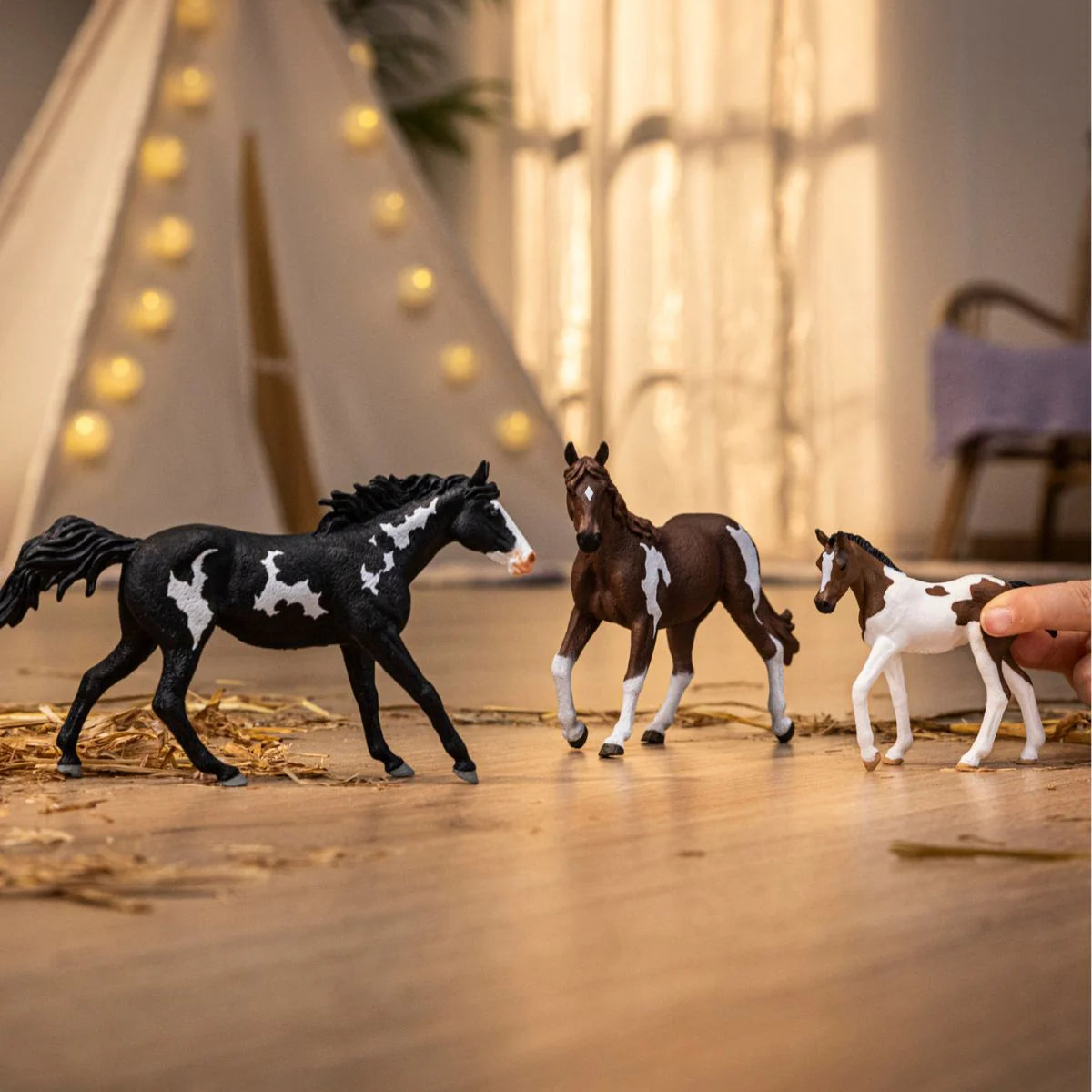 Three toy horses on a wooden floor with a blurred background