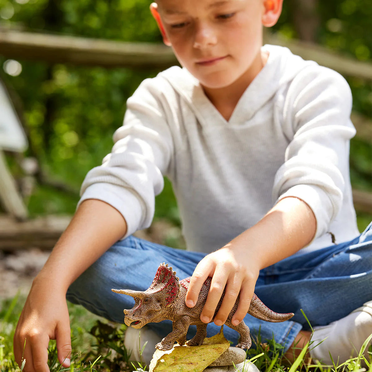 Child playing with a toy dinosaur outdoors