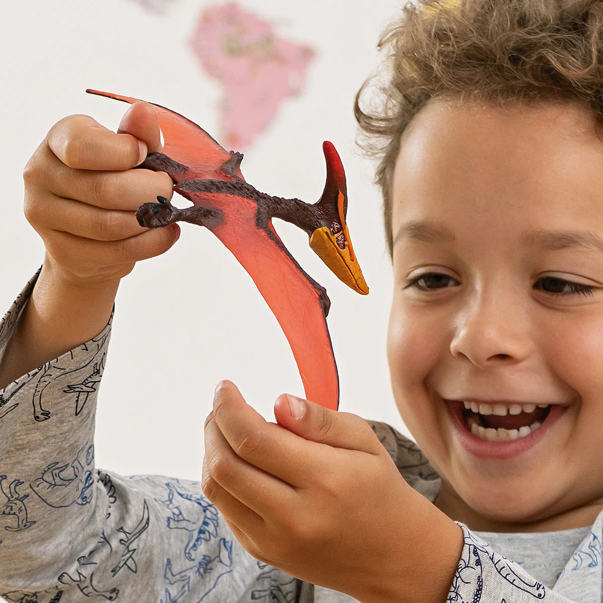 Child holding a red toy dragon with a plain background