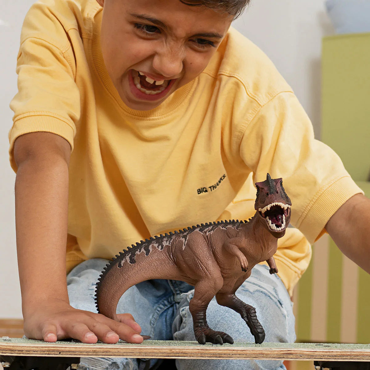 Child playing with a toy dinosaur on a table