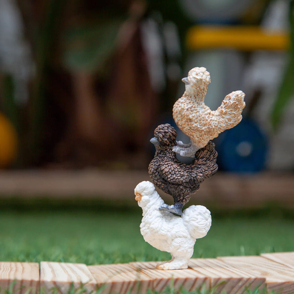 Two ceramic rooster figurines on a wooden platform with a blurred outdoor background