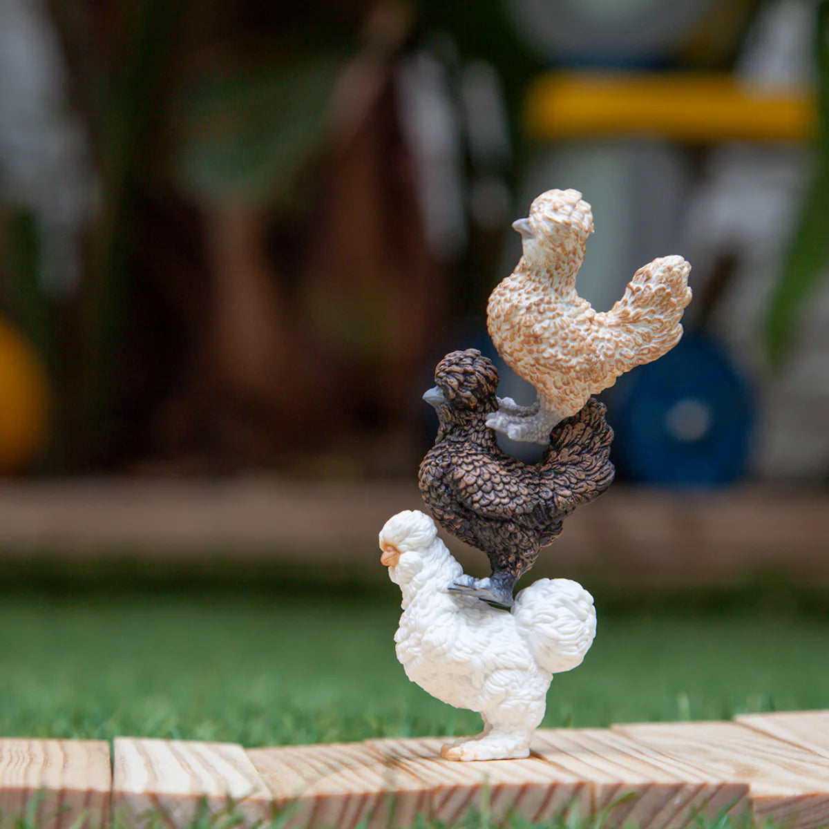 Two ceramic rooster figurines on a wooden platform with a blurred outdoor background