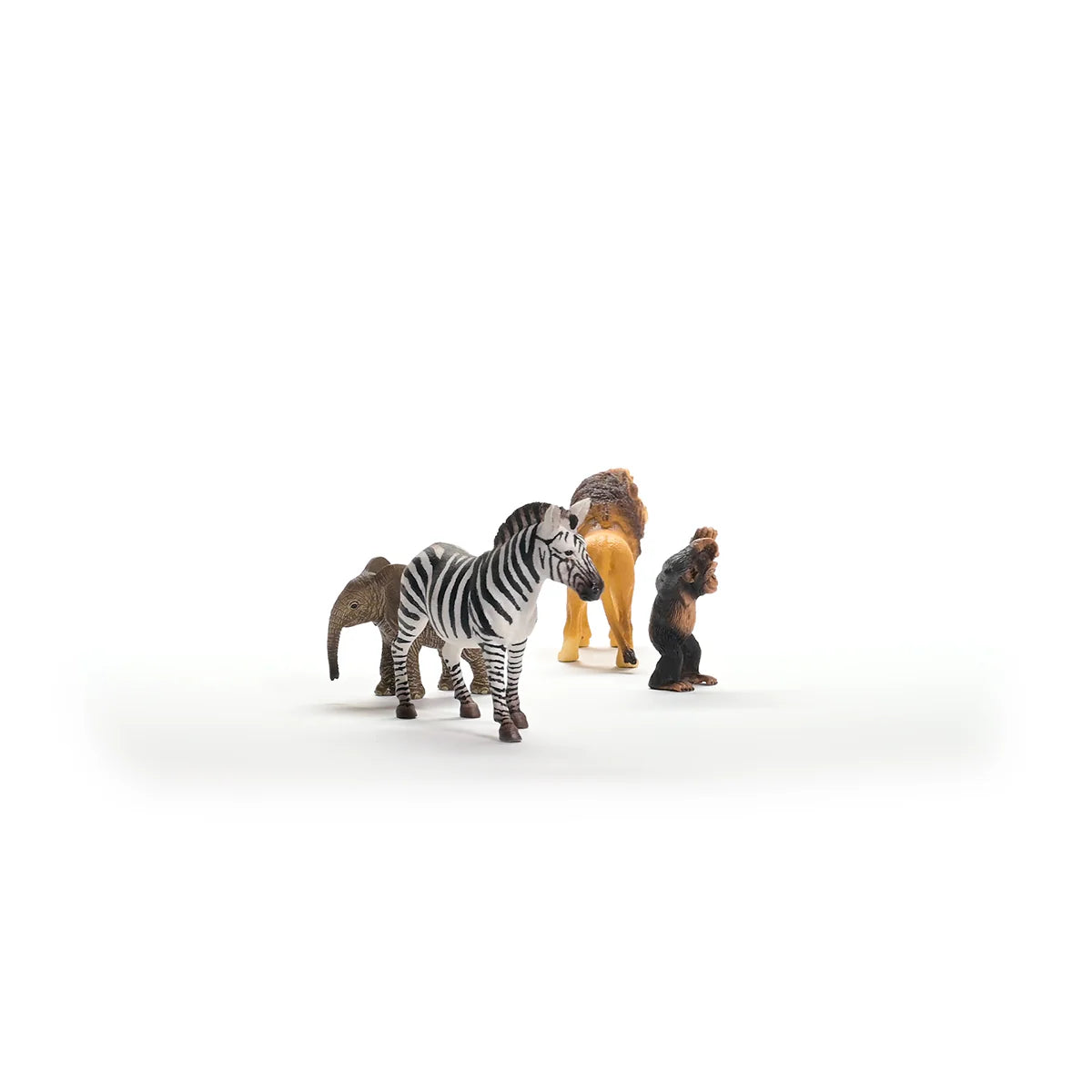 Toy figures of a zebra, lion, and monkey on a white background