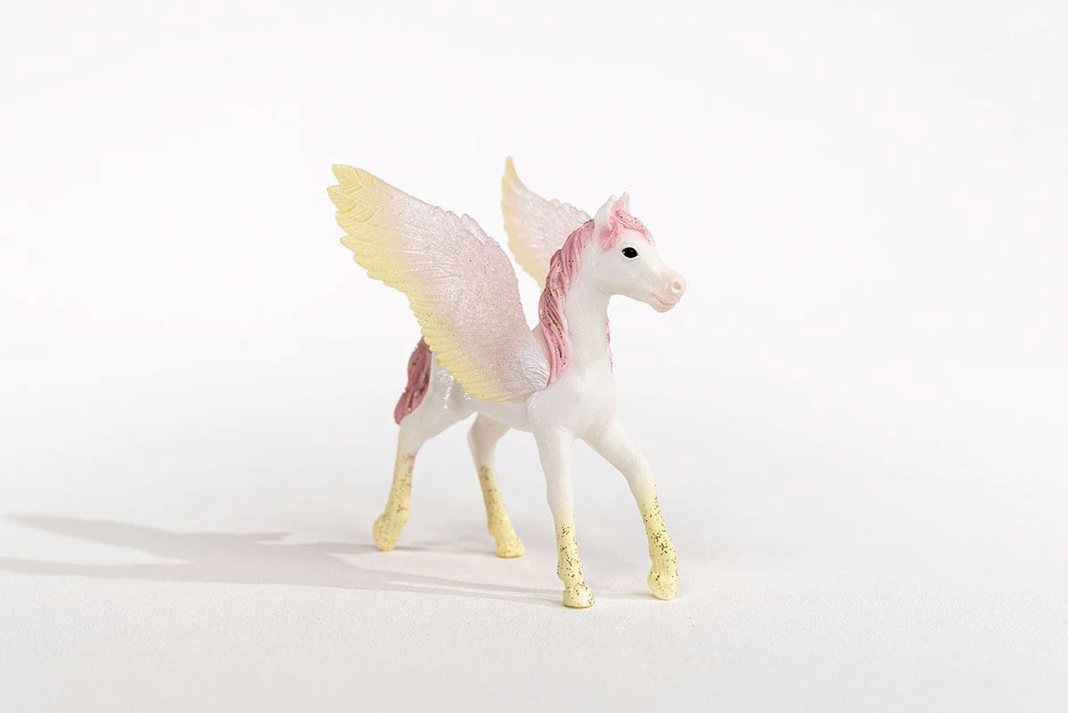 Toy Pegasus foal with pink mane and yellow wings on a white background