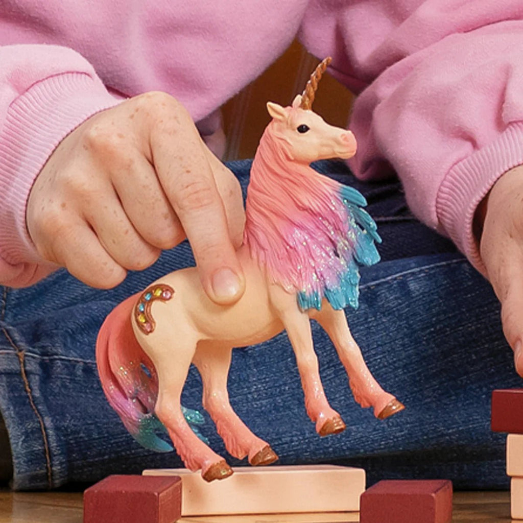 Child playing with a unicorn toy on a wooden surface