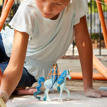 Child playing with toy mermaid and unicorn on a playground