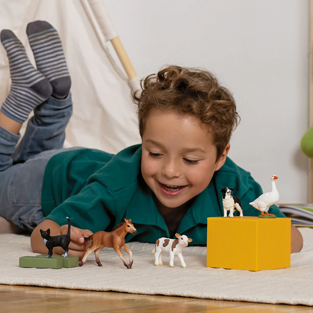 Child playing with farm animal toys on a carpeted floor.