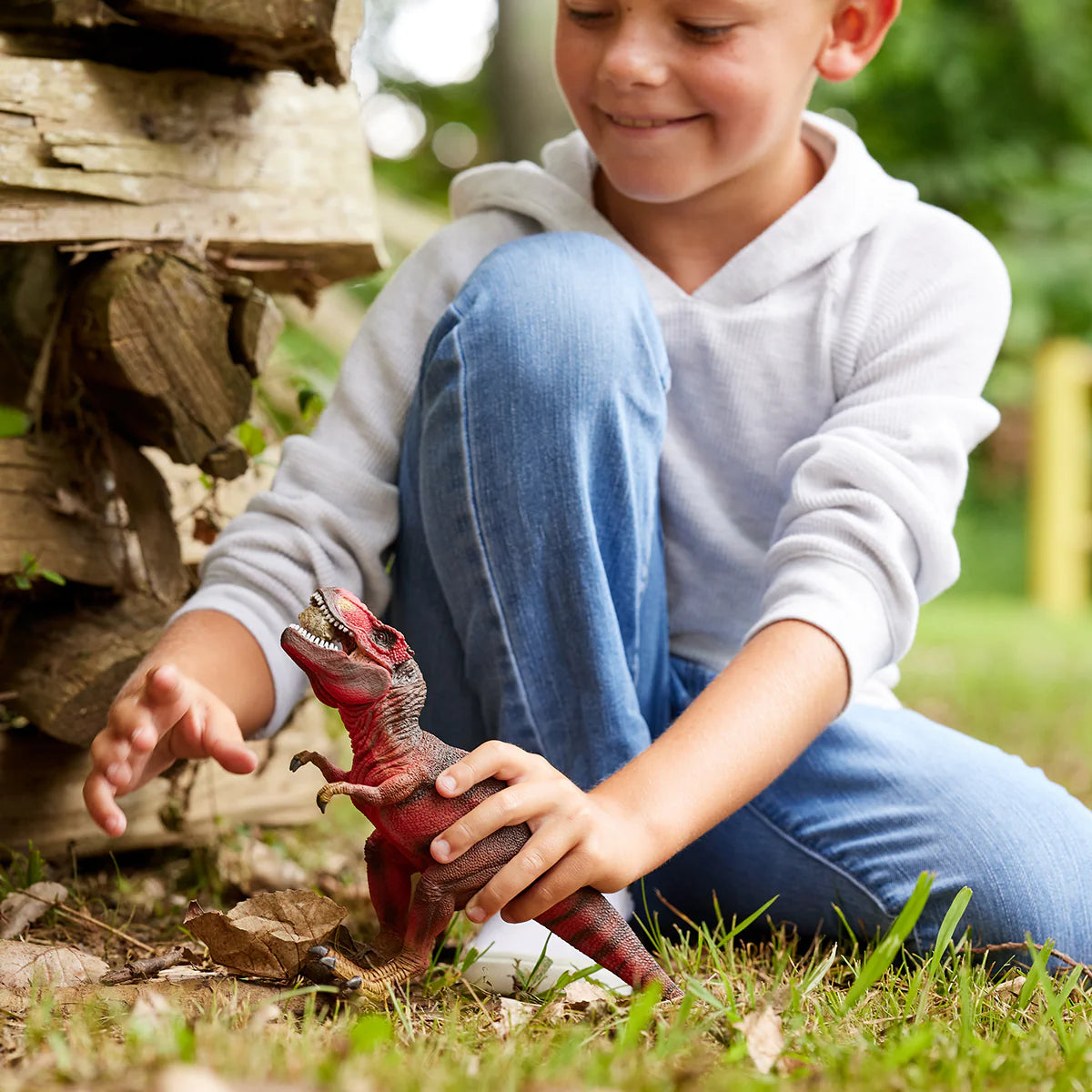 Child playing with a toy dinosaur outdoors