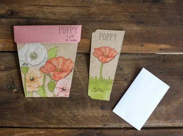 Two small paper packages labeled 'Poppy' on a wooden surface with a white card.