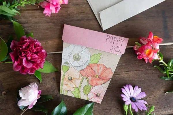 Floral notebook with 'Poppy' on a wooden surface surrounded by flowers