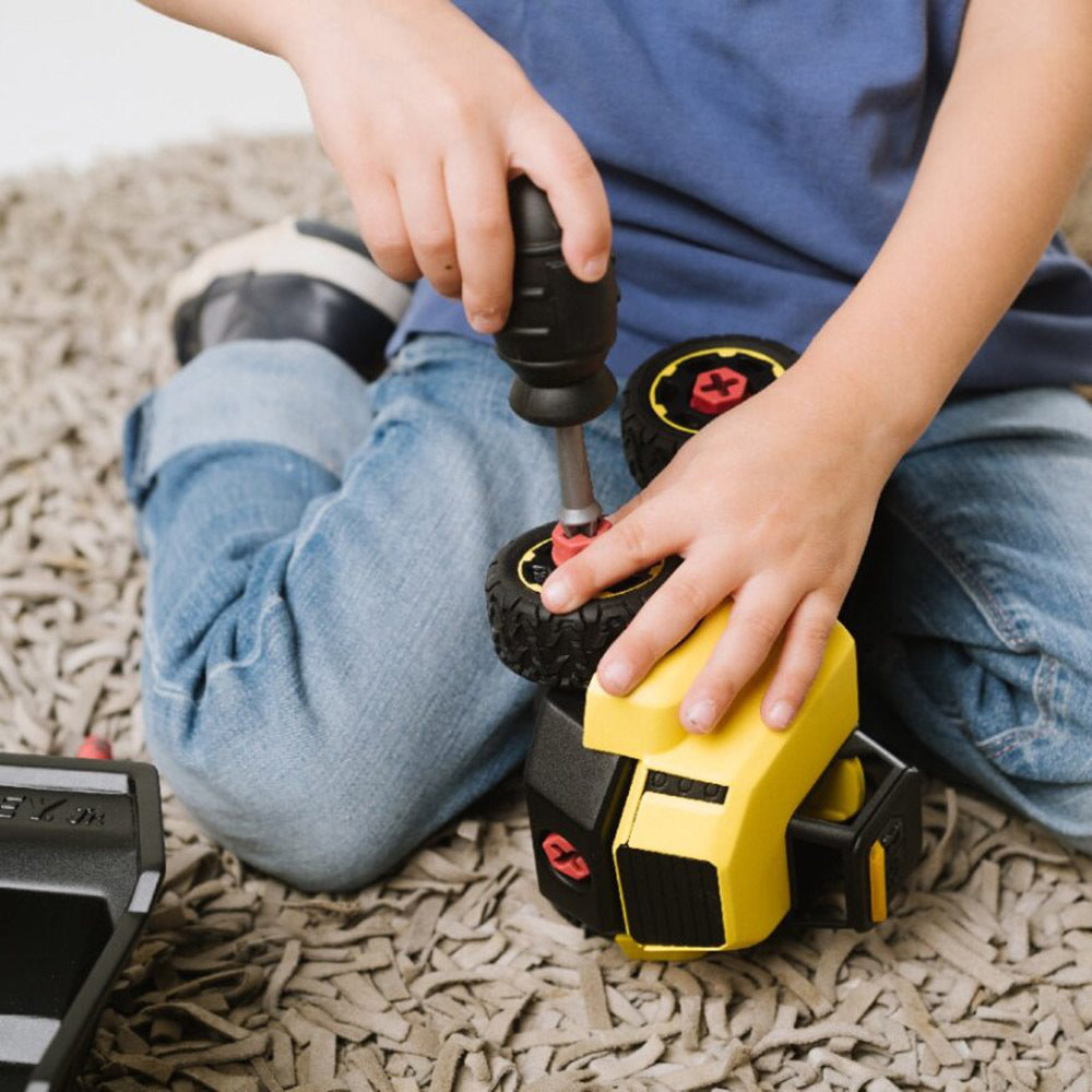 Child playing with toy drill and car on a carpeted floor