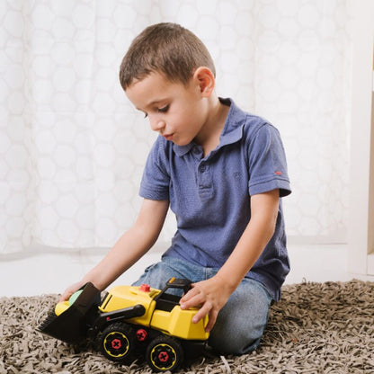 Child playing with a toy bulldozer on a carpeted floor.
