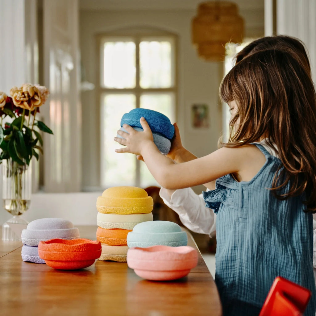 Child playing with colorful stacking toys on a wooden table.