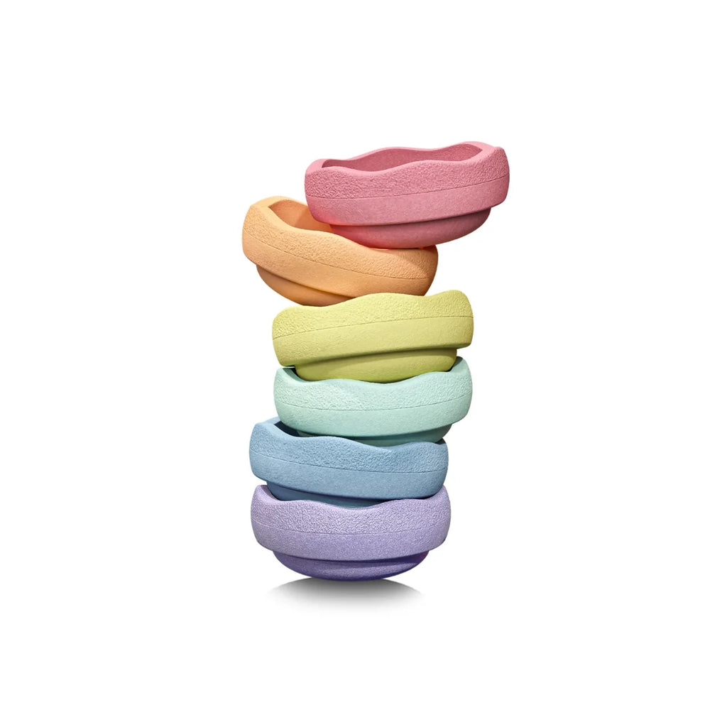 A stack of stepping stones in pastel rainbow colors, including pink, orange, yellow, light blue, and lavender, on a white background.