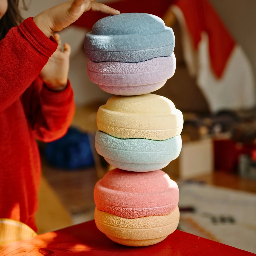 Colorful stack of stepping stones on a red surface with a blurred background.
