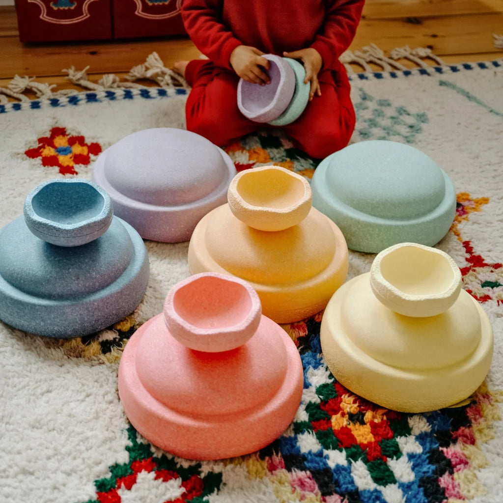 Colorful bowls on a patterned rug with a child in red clothing.