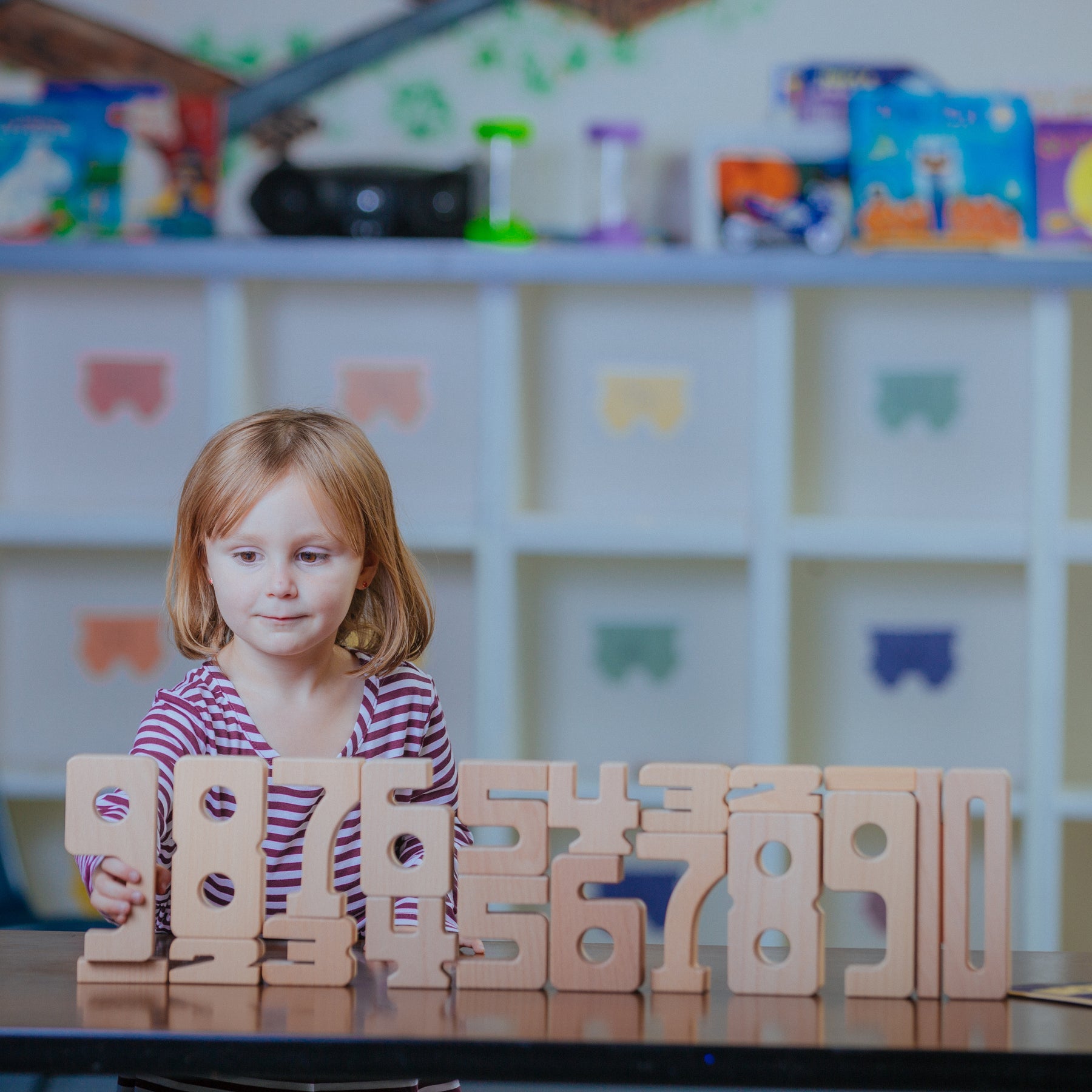 Child playing with wooden numbers in a classroom setting