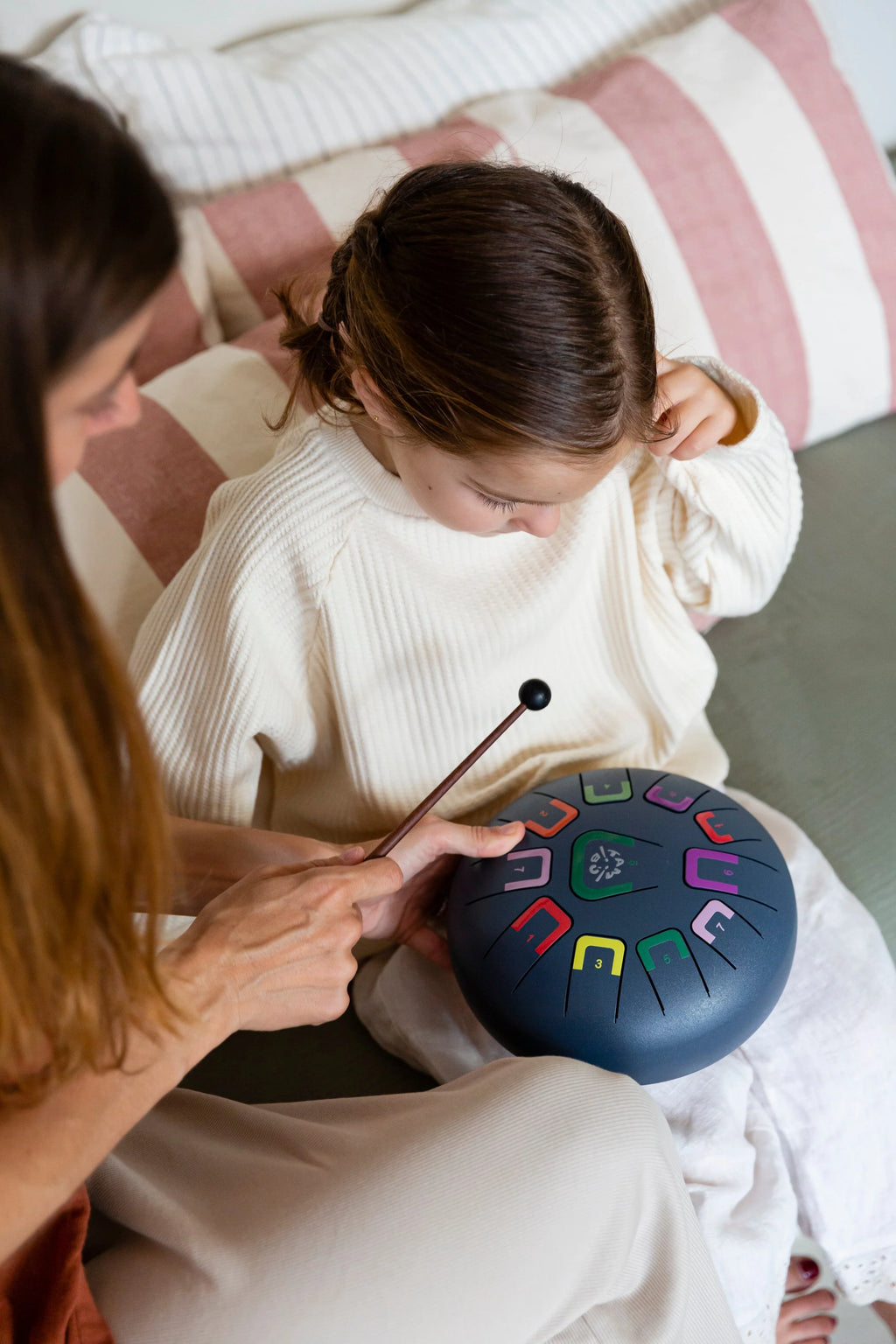 Two people sitting on a couch with a colorful hand drum in front of them.