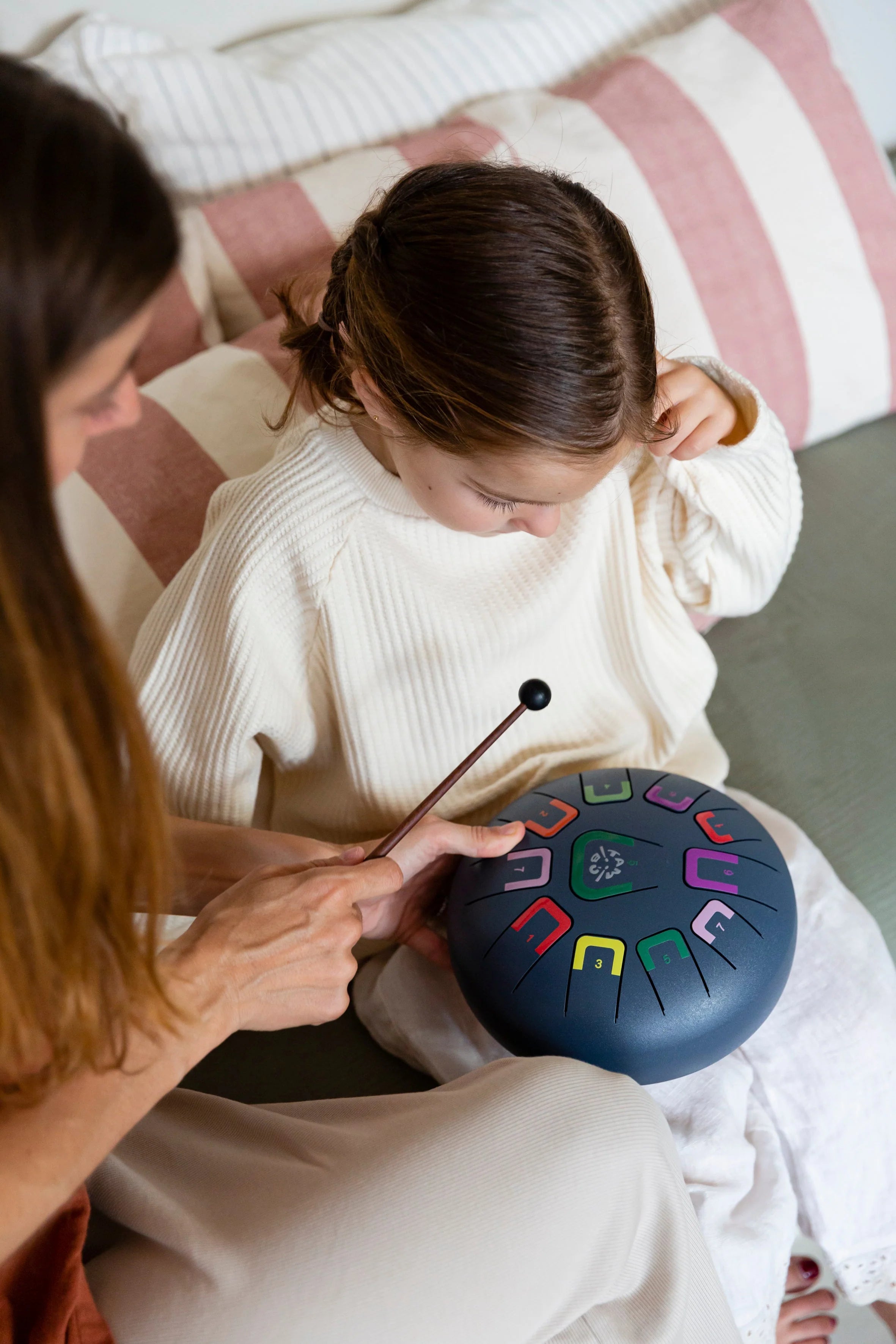 Two people sitting on a couch with a colorful hand drum in front of them.