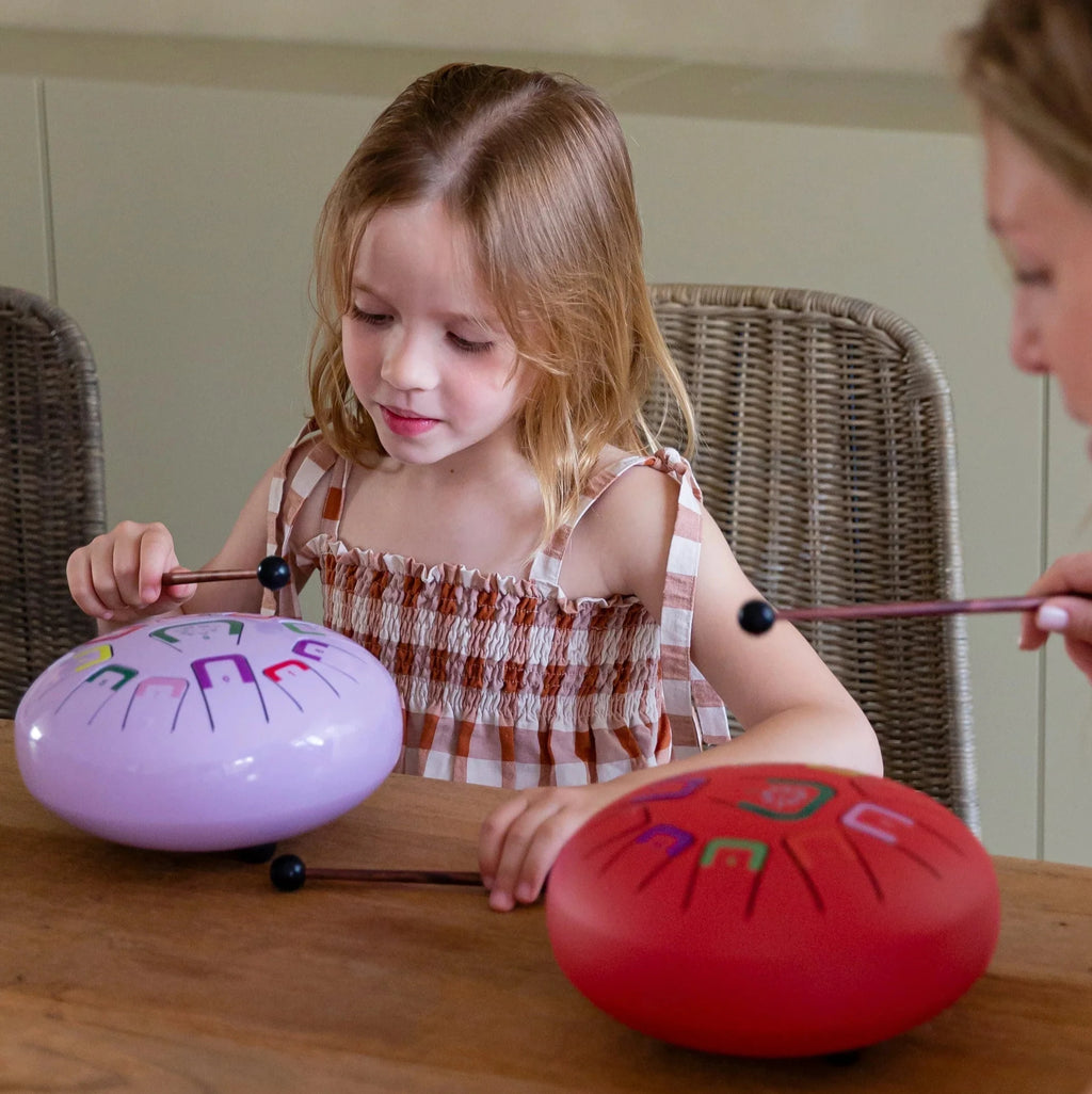 Two children playing with colorful percussion instruments at a table.