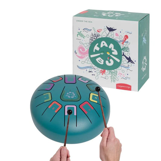 Turquoise metal tongue drum with colorful symbols and two drumsticks, next to a box with 'Tambor' branding.