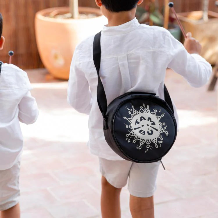 Child wearing a black round bag with white designs outdoors