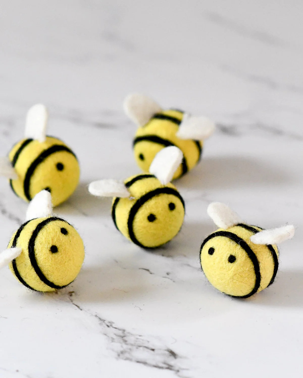 Five bee-shaped toys on a marble surface