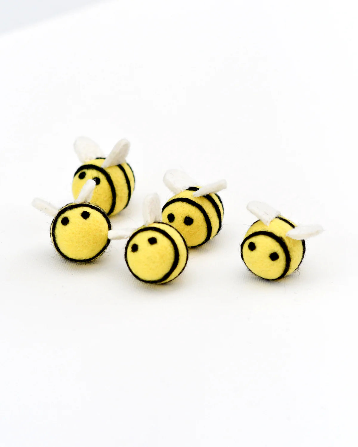 Five small plush bee toys on a white background