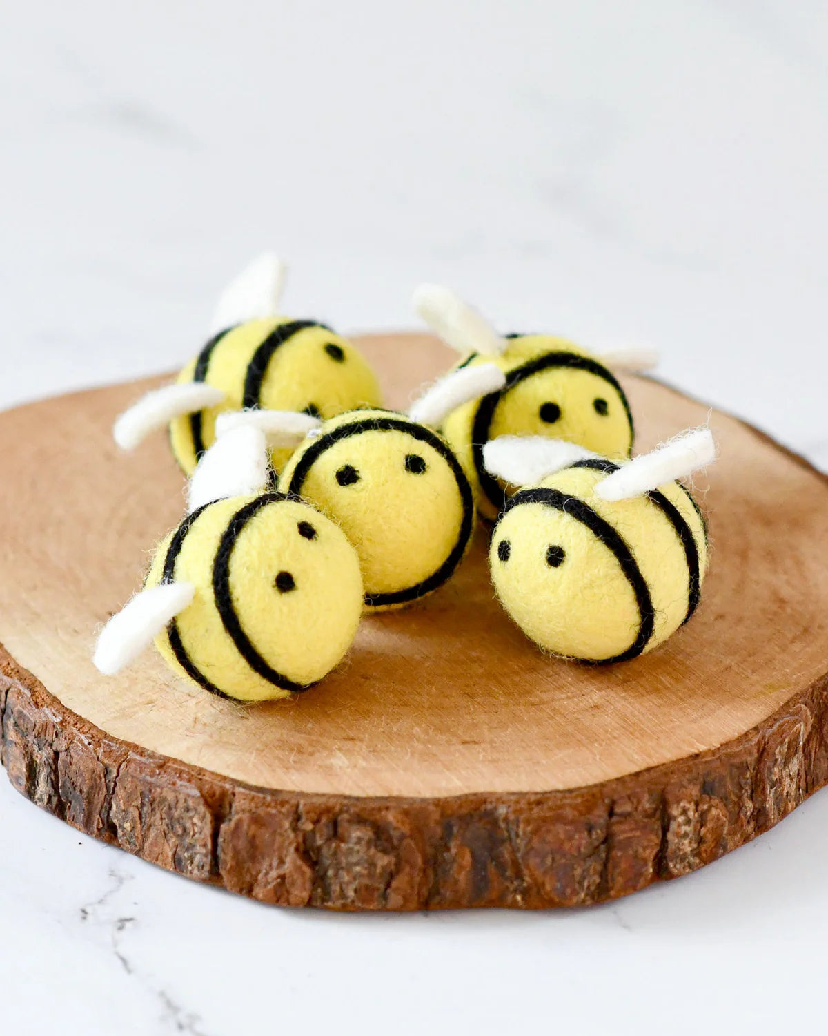 Four bee-shaped toys on a wooden block with a white background