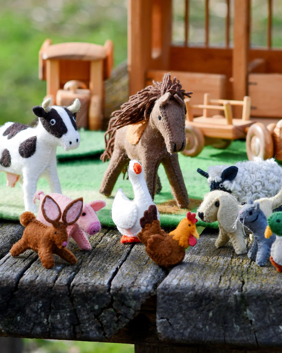 Felt animal toys on a wooden surface with a toy barn in the background