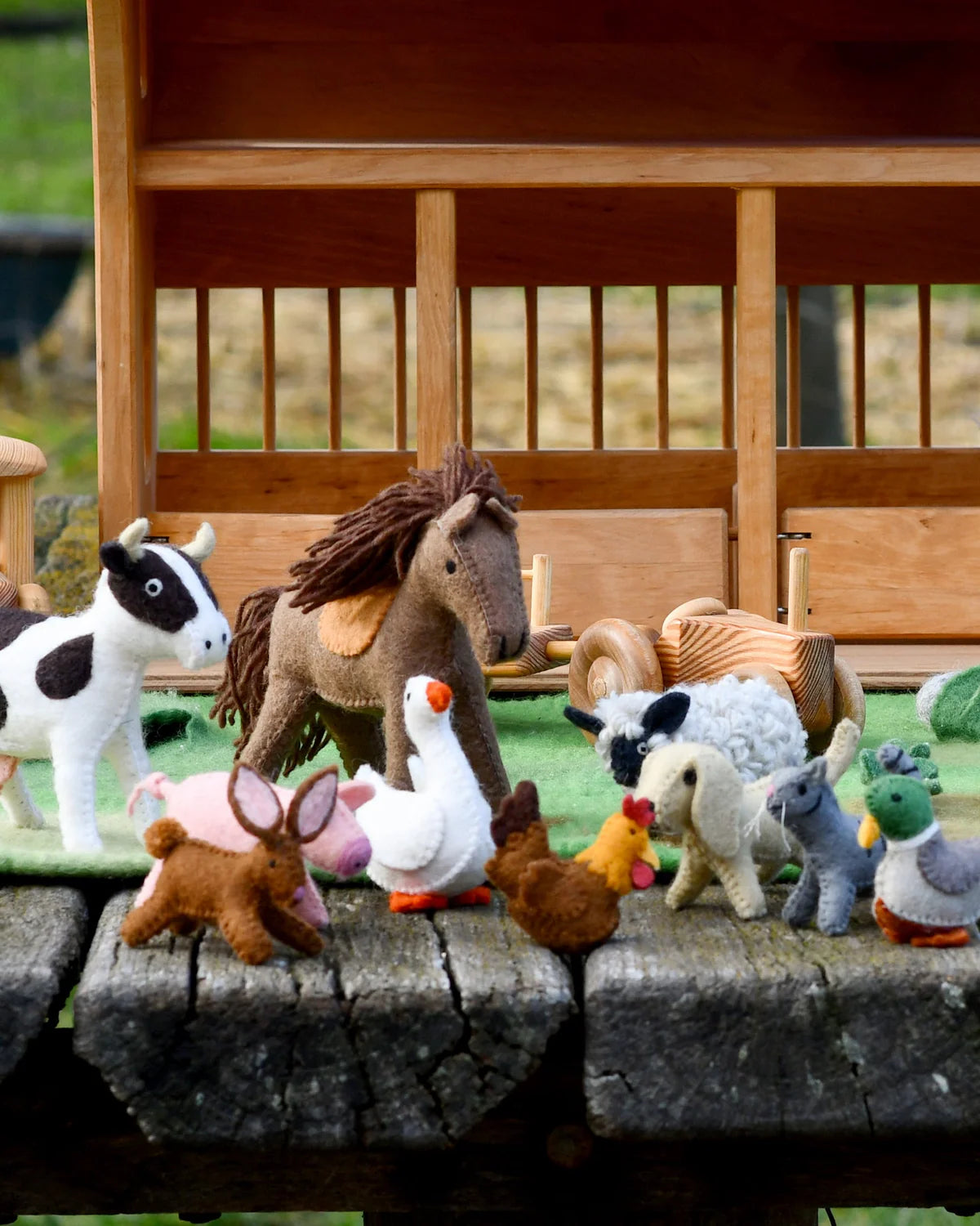 Collection of toy animals on a wooden platform with a wooden fence in the background