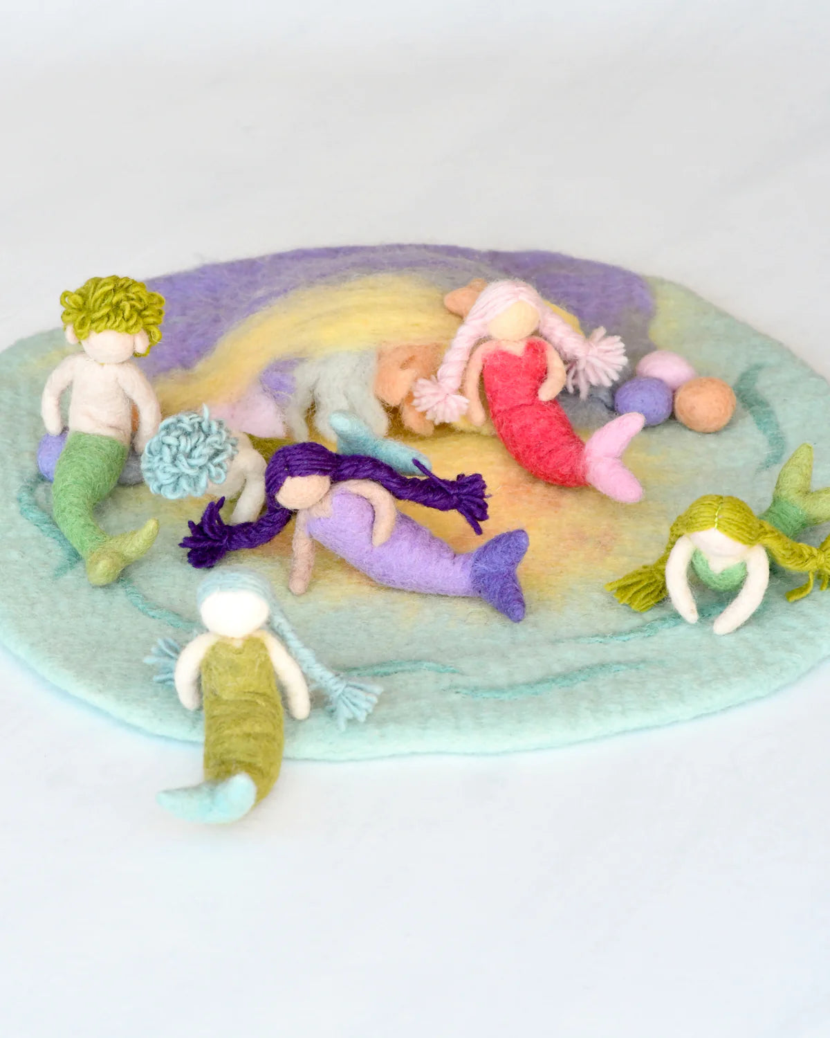 Colorful mermaid toys on a textured surface with a white background