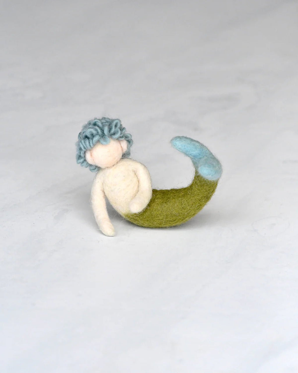 Mermaid toy with blue hair and green tail on a light gray background
