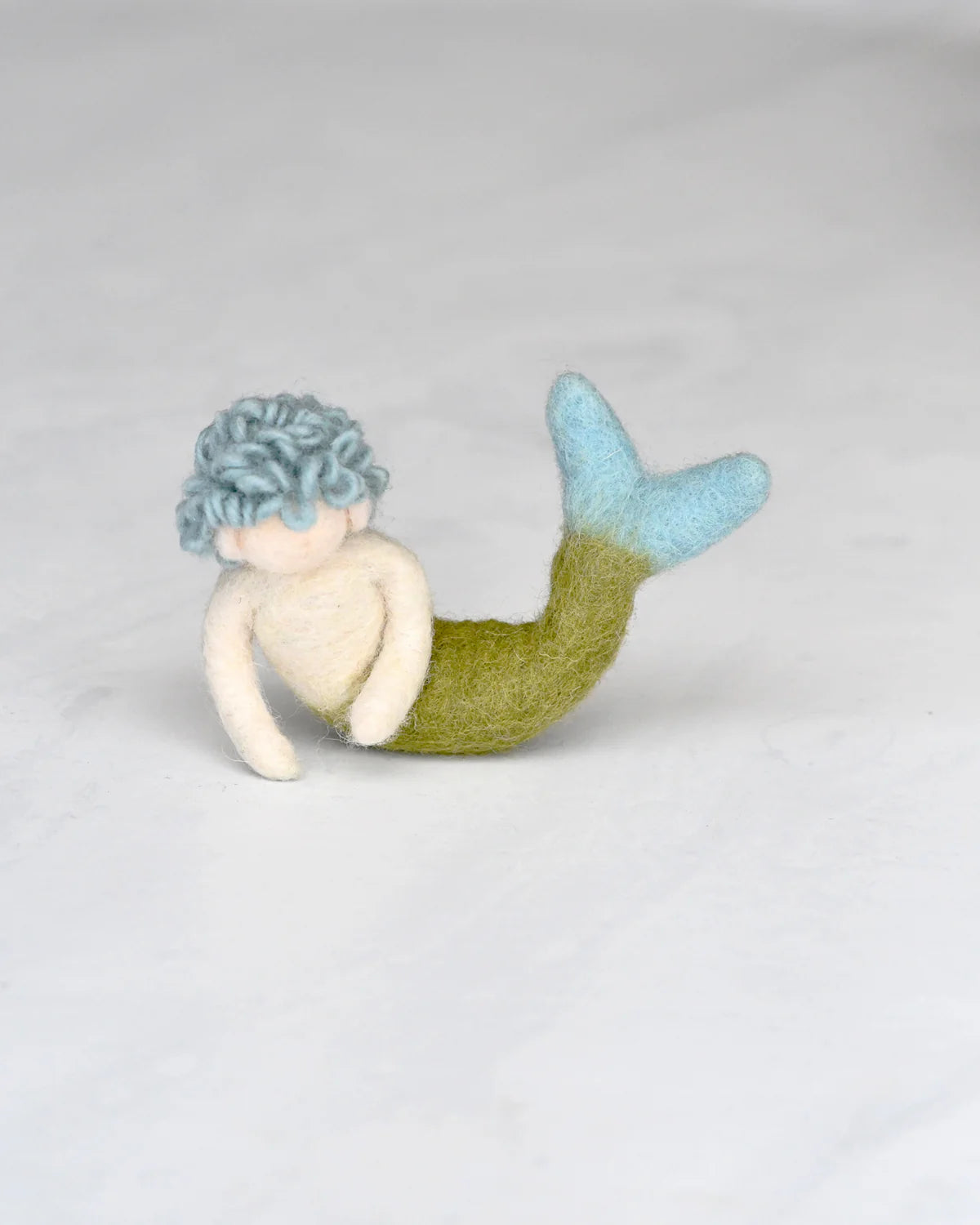 Mermaid toy with a blue top and green tail on a light gray background