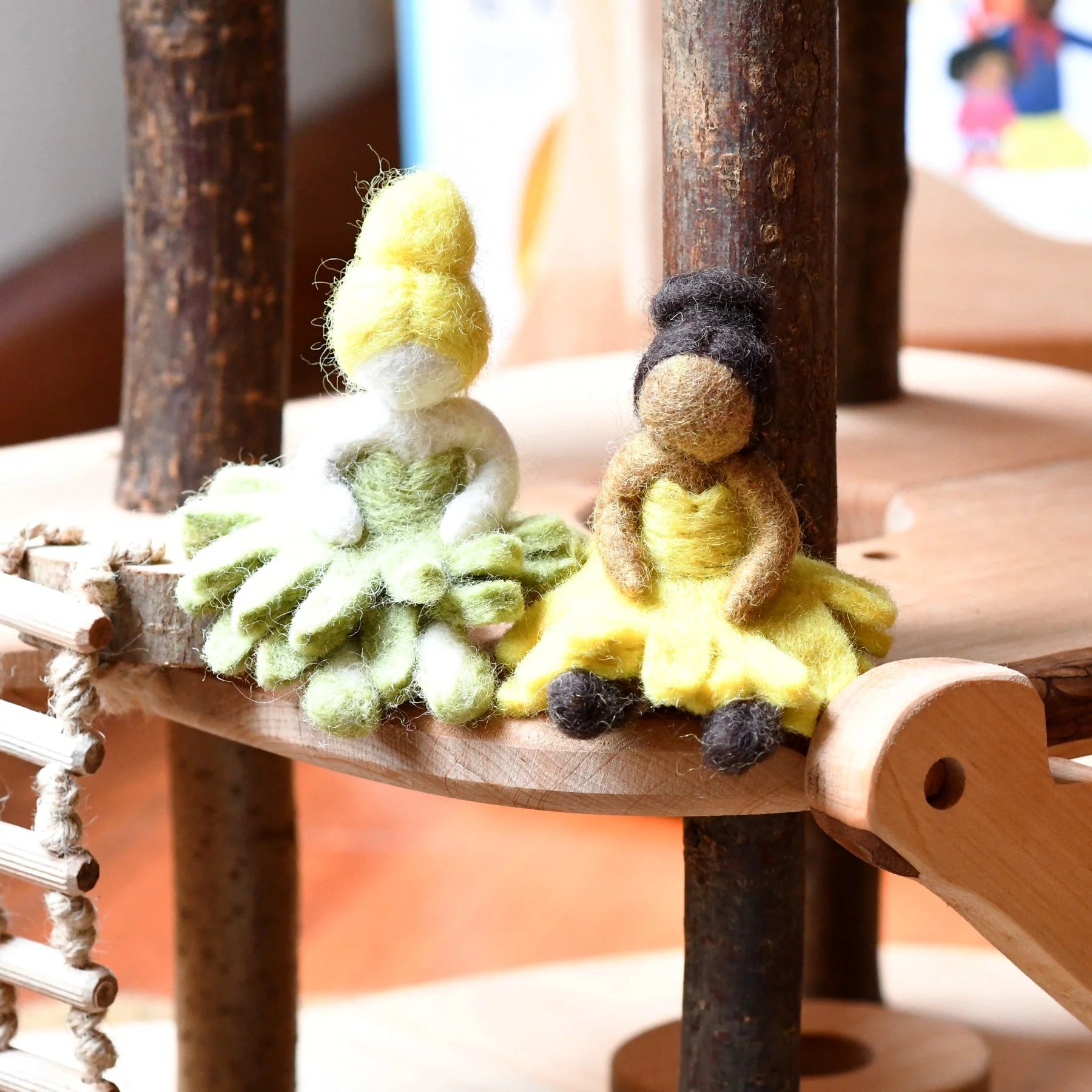 Two small figurines, one green and one yellow, sitting on a wooden surface.