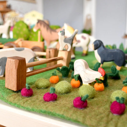 Model farm scene with animals and vegetables on a green surface
